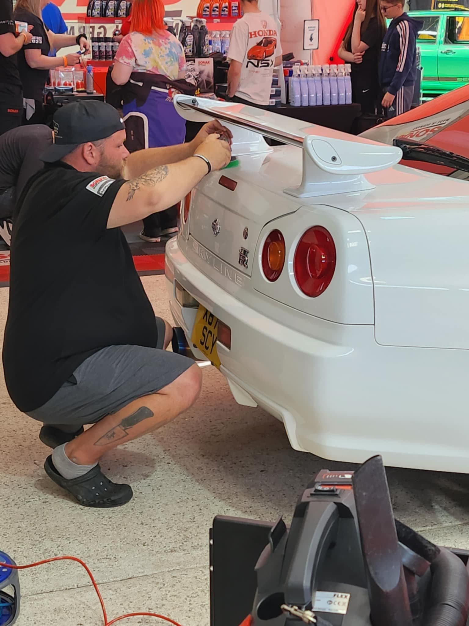 JJ team member detailing Nissan R34 at show